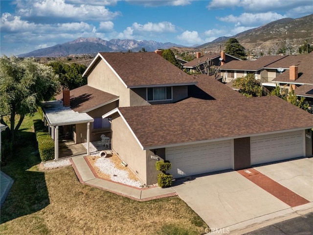 view of front facade with a garage, a front lawn, and a mountain view