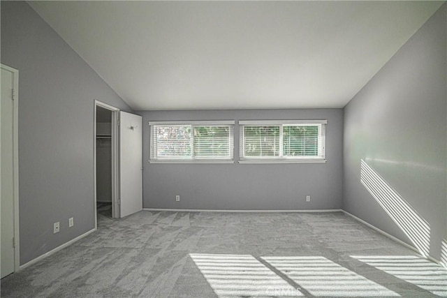 unfurnished bedroom with lofted ceiling, light colored carpet, a closet, and a spacious closet