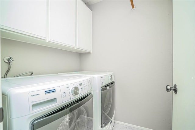 laundry room featuring cabinets, light tile patterned flooring, and washer and clothes dryer