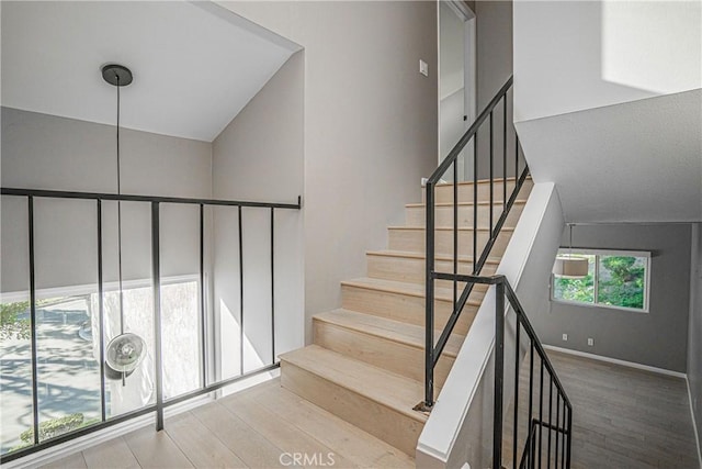 staircase with a high ceiling and hardwood / wood-style flooring