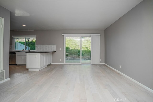 unfurnished living room featuring plenty of natural light and light hardwood / wood-style flooring