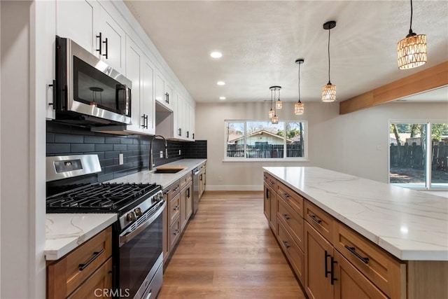 kitchen with pendant lighting, appliances with stainless steel finishes, and white cabinets