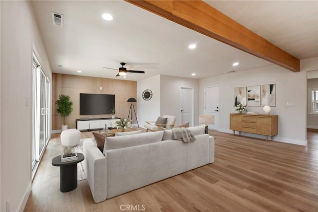 living room featuring ceiling fan, beam ceiling, and light hardwood / wood-style floors