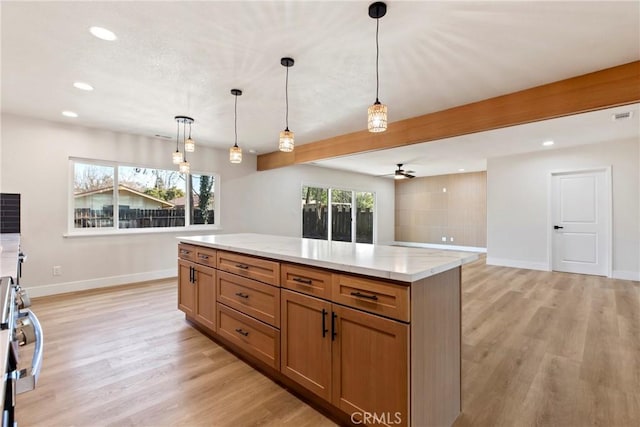 kitchen with light stone counters, ceiling fan, hanging light fixtures, and light hardwood / wood-style flooring