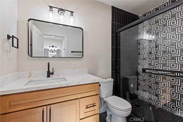 bathroom featuring vanity, toilet, and a shower with shower door