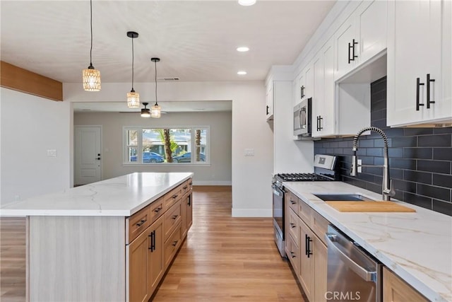 kitchen with white cabinetry, hanging light fixtures, stainless steel appliances, light stone countertops, and decorative backsplash