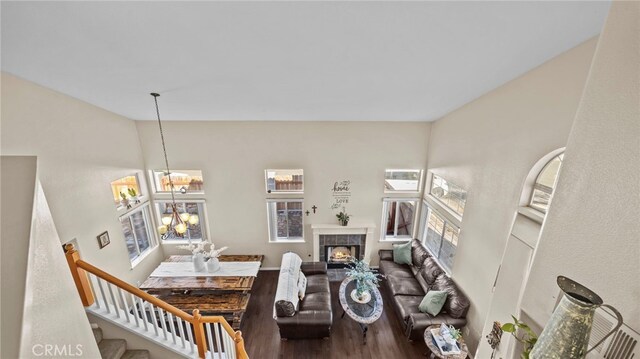 living room with a tile fireplace, a notable chandelier, wood-type flooring, and plenty of natural light