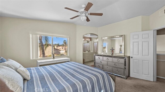 bedroom with ceiling fan, connected bathroom, and light carpet