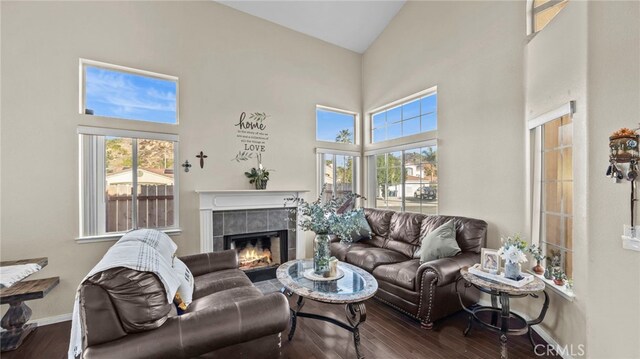 living room featuring a tiled fireplace, dark hardwood / wood-style floors, and a high ceiling