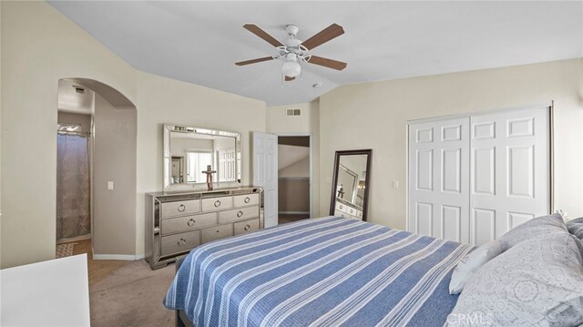 bedroom with ceiling fan, light colored carpet, vaulted ceiling, and a closet