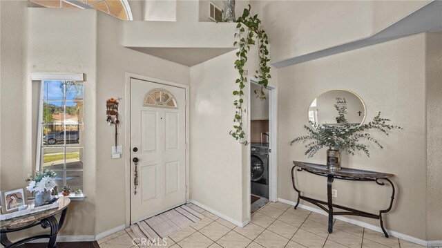 tiled foyer featuring washer / dryer and a towering ceiling