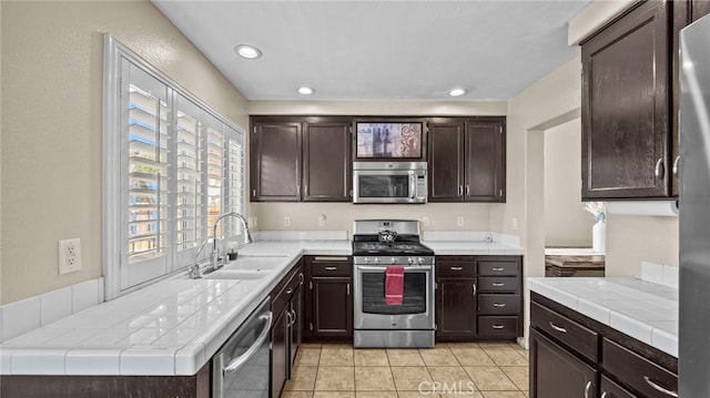 kitchen featuring dark brown cabinetry, sink, tile countertops, and stainless steel appliances