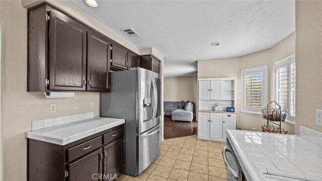 kitchen featuring tile counters, stainless steel fridge with ice dispenser, and dark brown cabinetry