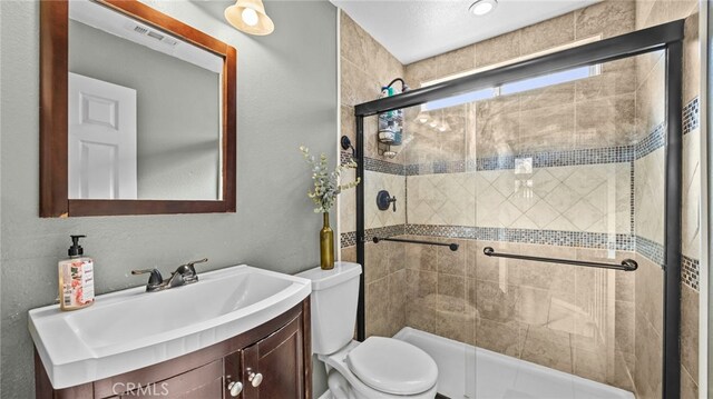 bathroom with toilet, a shower with shower door, and vanity