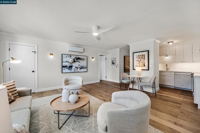 living room featuring a wall unit AC, light hardwood / wood-style floors, crown molding, ceiling fan, and sink