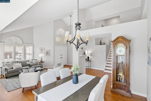 dining space featuring light hardwood / wood-style floors, high vaulted ceiling, a healthy amount of sunlight, and a notable chandelier