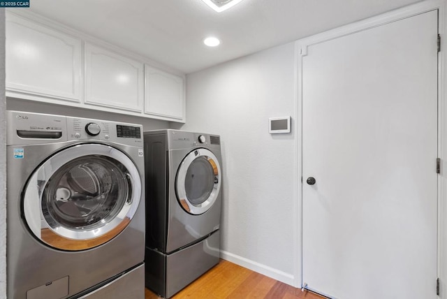 laundry room with independent washer and dryer, light wood-type flooring, and cabinets