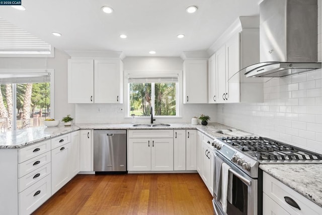 kitchen with white cabinets, appliances with stainless steel finishes, wall chimney exhaust hood, and sink