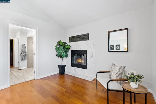 sitting room with a high end fireplace and hardwood / wood-style flooring