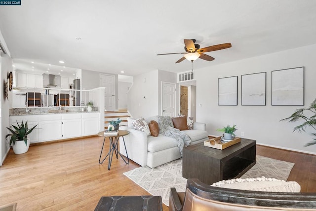 living room with ceiling fan, light hardwood / wood-style flooring, and sink