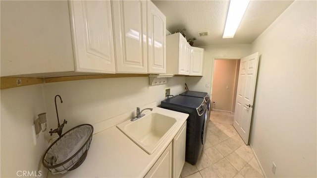 laundry room with cabinets, washing machine and clothes dryer, light tile patterned floors, and sink