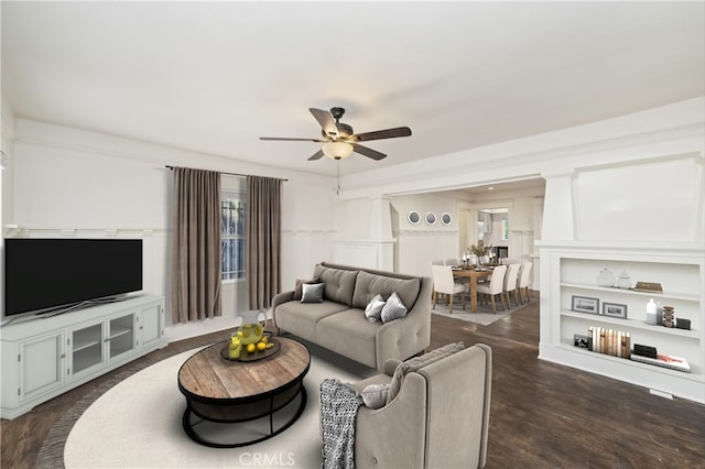 living room with ceiling fan and dark wood-type flooring