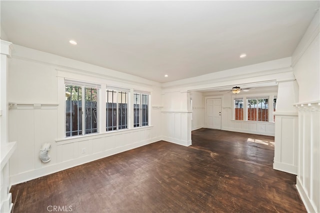 empty room featuring ceiling fan, a healthy amount of sunlight, and dark hardwood / wood-style floors