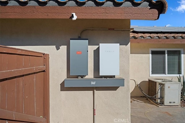 exterior details with central AC unit, a tile roof, and stucco siding