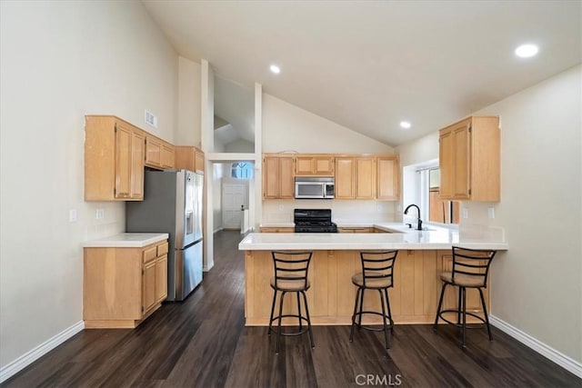 kitchen with appliances with stainless steel finishes, visible vents, light brown cabinets, and a peninsula