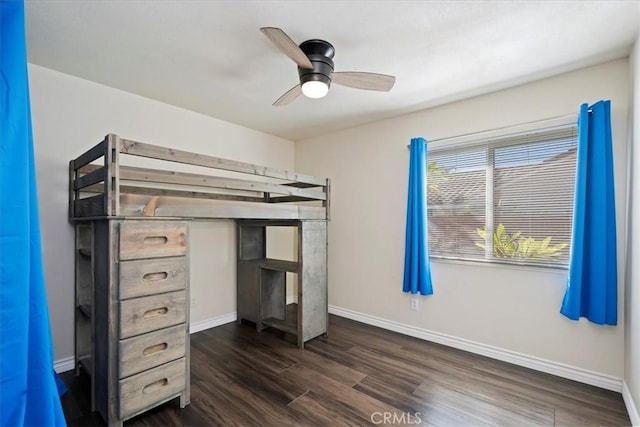 unfurnished bedroom featuring ceiling fan, baseboards, and dark wood finished floors