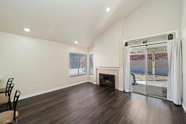 unfurnished living room with baseboards, dark wood-type flooring, and a wealth of natural light