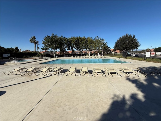 community pool featuring fence and a patio