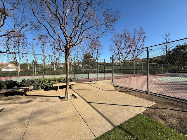 view of community featuring a tennis court and fence