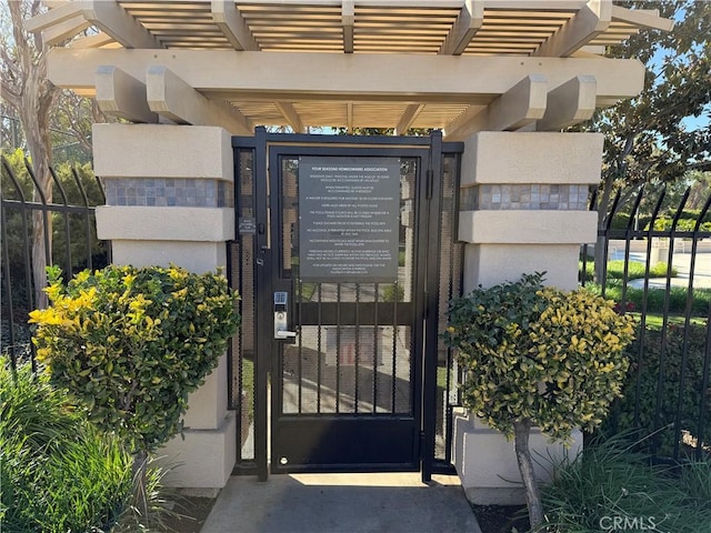 view of exterior entry featuring a gate, fence, and a pergola