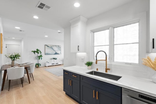 kitchen with light hardwood / wood-style floors, light stone countertops, sink, white cabinetry, and stainless steel dishwasher