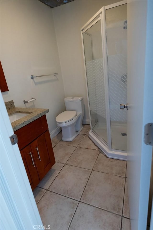 bathroom featuring vanity, a shower with shower door, tile patterned floors, and toilet