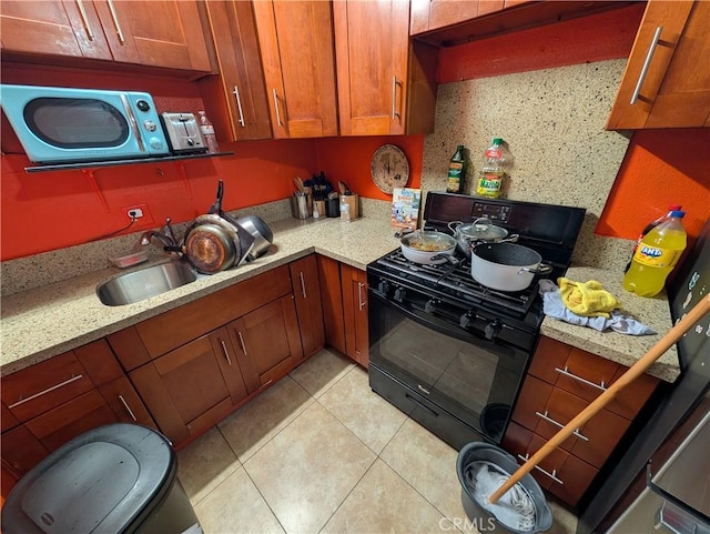 kitchen featuring sink, black range with gas stovetop, decorative backsplash, light tile patterned floors, and light stone counters