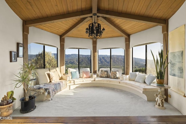 sunroom featuring vaulted ceiling with beams, an inviting chandelier, a wealth of natural light, and a mountain view