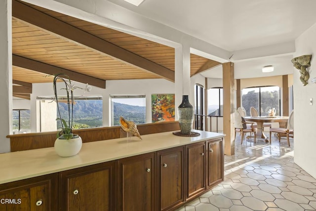 kitchen with wooden ceiling, beamed ceiling, a mountain view, dark brown cabinets, and an inviting chandelier