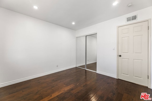 unfurnished bedroom featuring dark hardwood / wood-style flooring and a closet