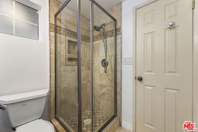 bathroom with a shower with shower door and toilet