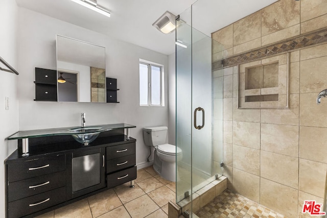 bathroom with toilet, a shower with shower door, vanity, ceiling fan, and tile patterned flooring