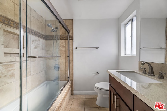 full bathroom with toilet, tile patterned floors, vanity, and bath / shower combo with glass door