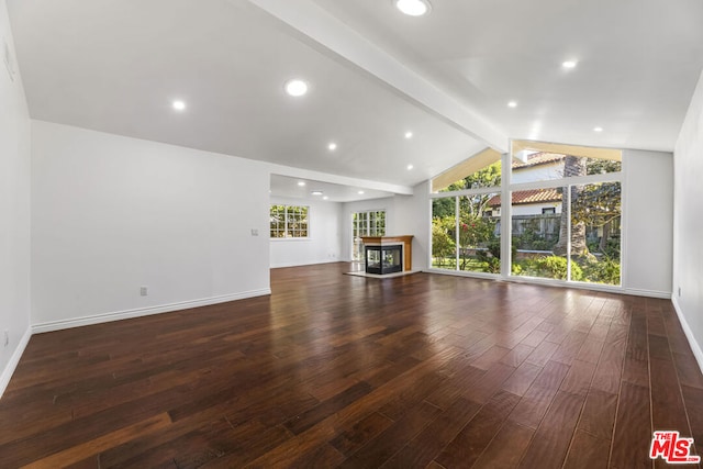 unfurnished living room featuring a multi sided fireplace, a healthy amount of sunlight, dark hardwood / wood-style floors, and lofted ceiling with beams