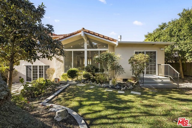 rear view of property featuring a lawn and a sunroom