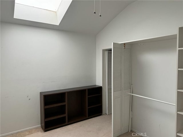 walk in closet with lofted ceiling with skylight and light colored carpet