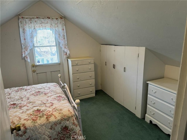 bedroom with a textured ceiling, dark colored carpet, and vaulted ceiling