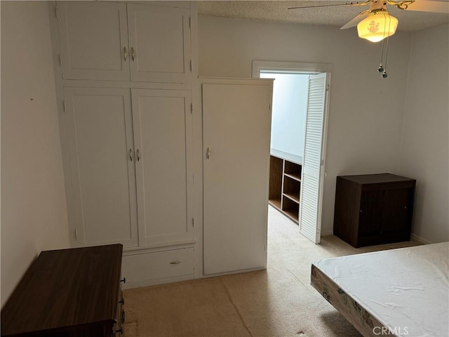 unfurnished bedroom featuring a textured ceiling, ceiling fan, and light carpet