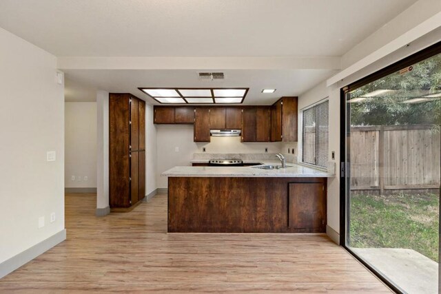 kitchen with sink, light wood-type flooring, and kitchen peninsula