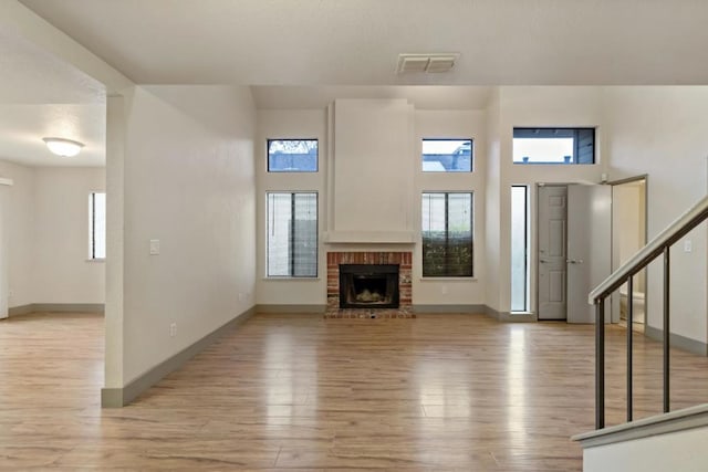 unfurnished living room with a high ceiling, a fireplace, and light hardwood / wood-style flooring